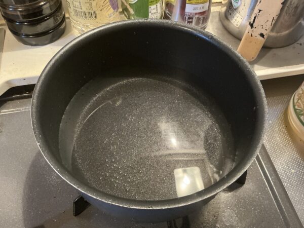 鍋に水を入れてお湯を沸かし、豚肉を茹でる準備をする様子