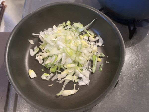 長ネギを調理バサミでカットしてフライパンに入れる様子