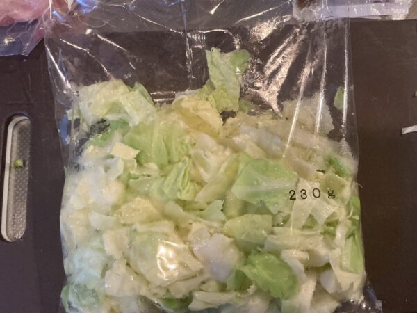 袋に切り込みを入れたキャベツを電子レンジで加熱し、皿に広げる工程