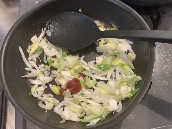 フライパンに油と豆板醤を加え、長ネギがクッタリするまで弱火で炒める工程