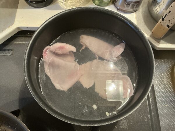 茹で上がった豚肉をザルに上げ、キャベツの上に盛り付ける工程