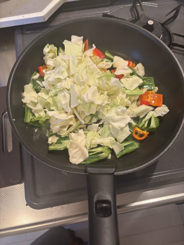 キャベツと水を加え、強火で油を絡めながら炒める様子