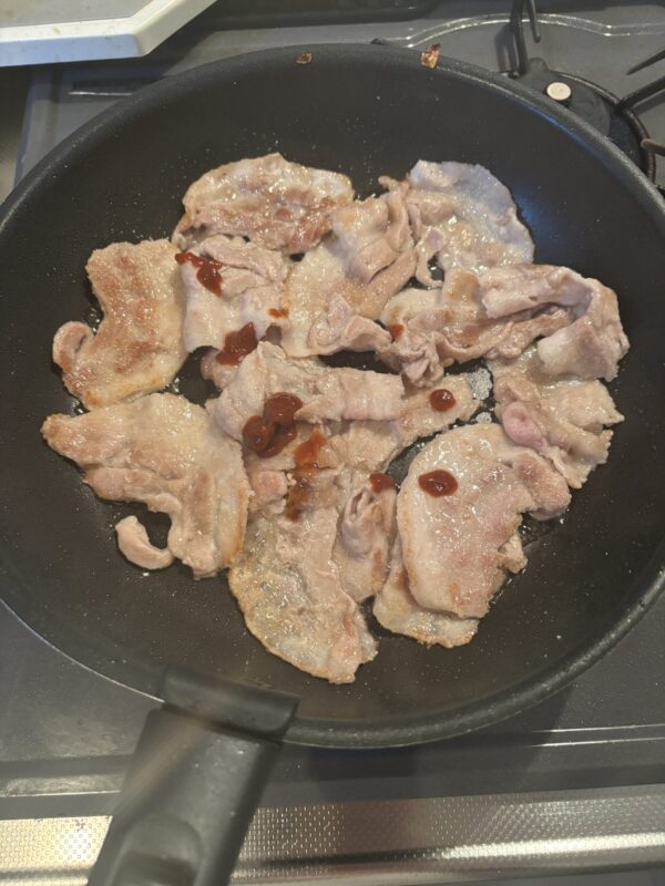 焼き色のついた豚肉に豆板醤を加え、香りが出るまで炒める工程