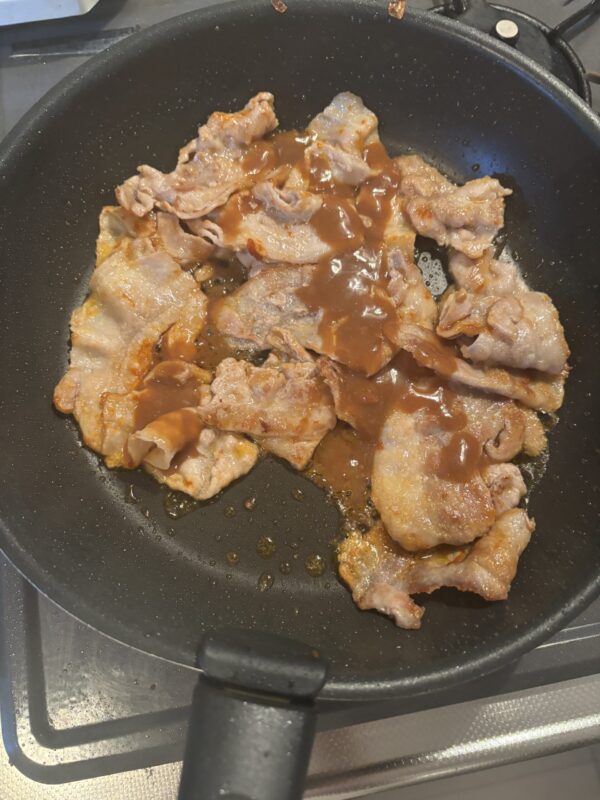 豆板醤の油が赤くなったところで特製たれを加えて炒め合わせる様子