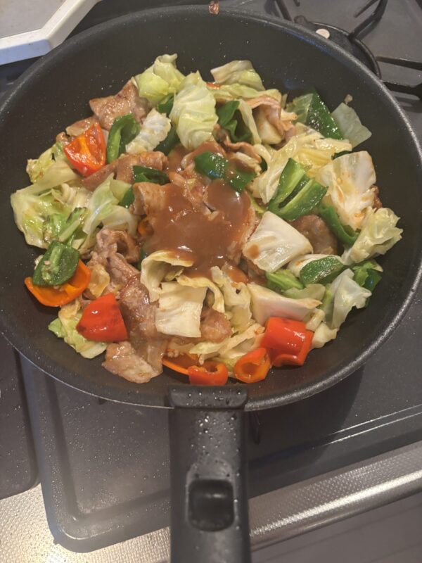 仕上げに炒めておいた野菜をフライパンに戻し、強火で一気に仕上げる様子