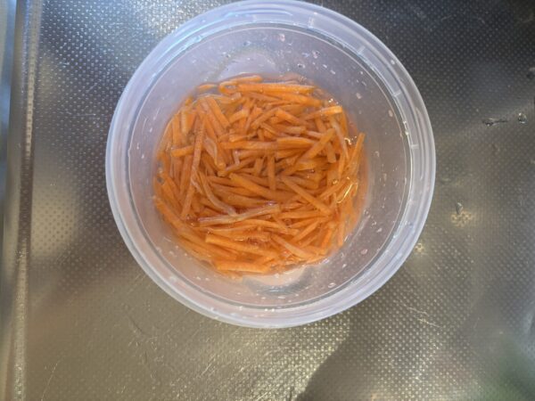 副菜の下ごしらえとして、耐熱容器に入れたにんじんを電子レンジで加熱する様子