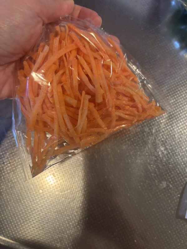 ビニール袋に入れたニンジンにオリーブオイルと塩を加え、揉み込む工程